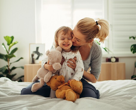 Bonding time: Mom and her Daughter Playing With Stuffed Toys on the Bed in the Morning
